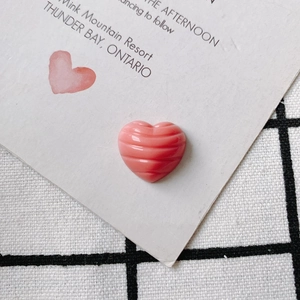 Makro-Detail eines rosa herzförmigen DIY-Anhängers mit Streifentextur auf schickem Hintergrund