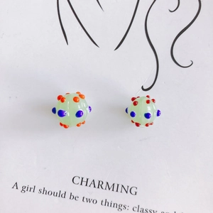 Detailed view of round light green glass beads with colorful 3D polka dots for DIY jewelry
