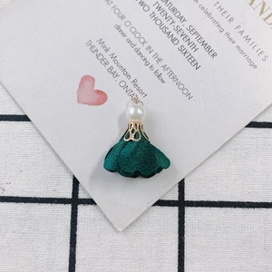 Macro shot of elegant dark green fabric flower pendant with pearl and gold metal holder