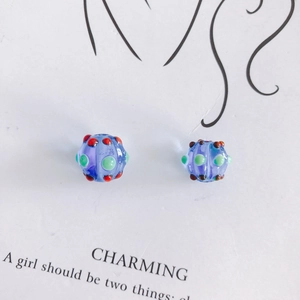 Detail of lavender glass beads with colorful dots on a white artistic card backdrop