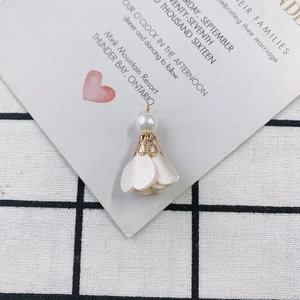 Macro view of white fabric flower petal pendant with pearl and gold hollow filigree cap