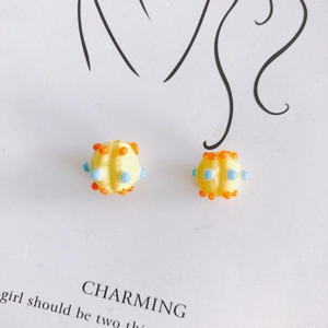 Macro shot of yellow DIY cartoon glass beads with orange and blue dots for jewelry making