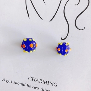 Detail of dark blue round glass charm beads with orange and yellow 3D pop art dots