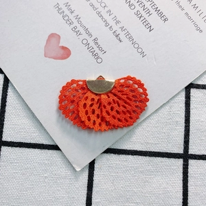 Detailed view of an orange fan-shaped lace pendant with a golden metal ring for DIY jewelry