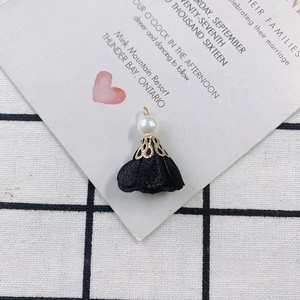 Detail of vintage handmade black fabric flower charm with pearl and gold metal cap