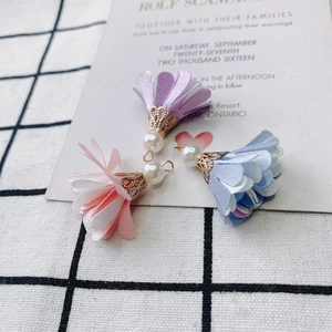 Detail of DIY fabric flower charms with gold caps and pearls on an elegant background