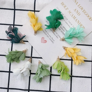 Détail de pompons fleurs en mousseline colorée avec embouts dorés pour création de bijoux DIY