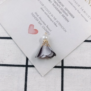 Close-up of elegant grey fabric flower pendant with a white pearl and gold filigree cap
