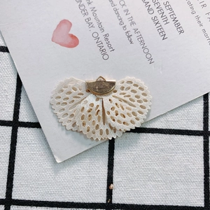 Macro shot of fan-shaped beige lace accessory with golden metal clasp for DIY jewelry
