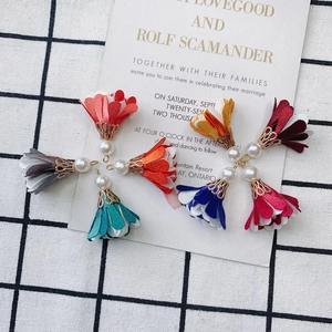 Macro shot of colorful fabric flower charms with pearl accents for DIY jewelry making