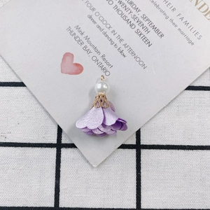 Macro shot of purple fabric flower tassel pendant with white pearl and gold filigree cap