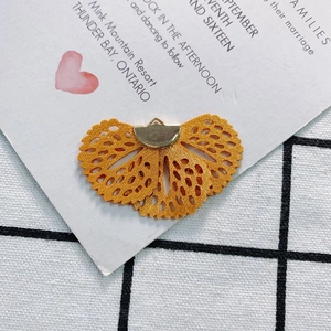Detailed macro view of yellow embroidered fan charm with golden metal clip for DIY jewelry