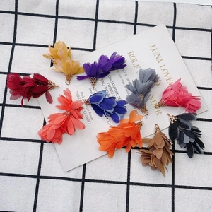 Gros plan de breloques fleurs en tissu coloré avec calottes dorées pour bijoux DIY créatifs