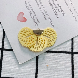 Close-up of yellow fan-shaped lace accessory with golden metal clasp for DIY crafts