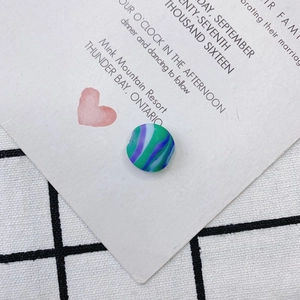 Gros plan d'une perle en verre plate avec texture marbrée verte et violette sur carte