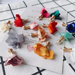 Primer plano de colgantes de rosas de tela coloridas con hilo dorado, perlas y ganchos