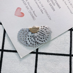 Macro detail of fan-shaped embroidery fabric charm with golden metal cap for DIY jewelry