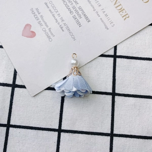 Close-up of light blue fabric flower pendant with white pearl and gold wire for DIY jewelry