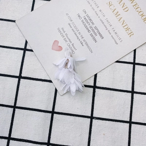 Détail d'un pendentif fleur en tissu blanc avec anneau doré pour création de boucles d'oreilles