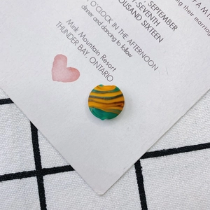 Gros plan d'une perle ronde plate en résine avec texture marbrée jaune orange et verte