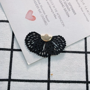 Black lace fan-shaped DIY jewelry accessory with a gold metal clasp on a grid background