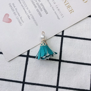 Detailed shot of peacock green fabric flower tassel pendant with white pearl and gold ring