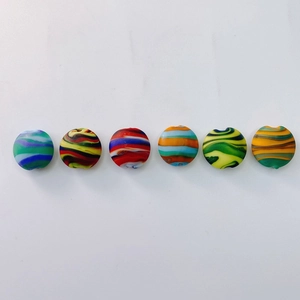 Détail de six perles plates rondes en verre avec motifs en spirale colorés