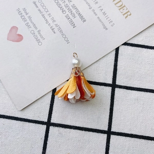 Detail view of handmade layered fabric flower pendant with a pearl and golden clasp
