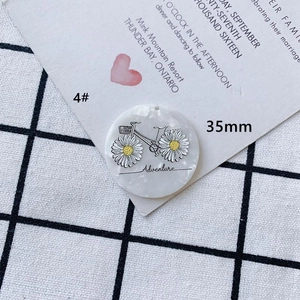Vue macro d'un pendentif en acrylique de 35mm avec dessin de vélo aventure et marguerites