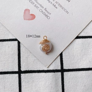 Detail view of a 18x12mm pearl charm with gold wire wrap and a secure metal hanging loop