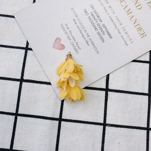 Détails macro de breloques fleurs en tissu jaune avec capuchons dorés pour bijoux DIY