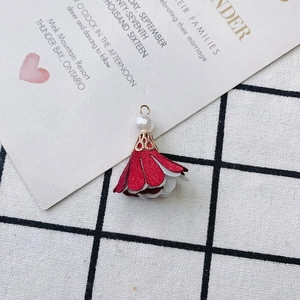 Detail of red and white fabric flower pendant with a white pearl and gold metal cap