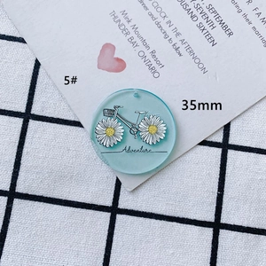 Détail d'un pendentif en acrylique bleu 35mm avec vélo marguerite et gravure Adventure