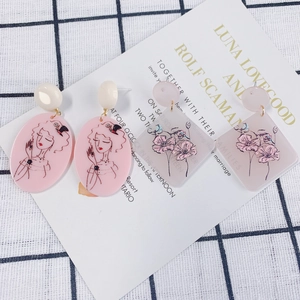 Detailed view of pink acrylic pendants with vintage lady illustration and floral patterns