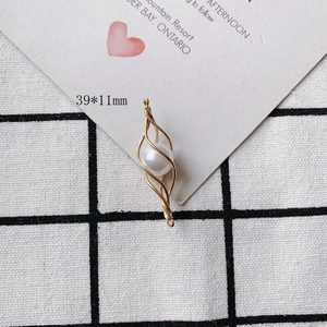 Detail of gold copper wire wrapped white pearl pendant accessory 39x11mm on plaid base