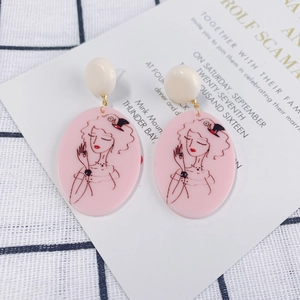 Detail of pink acrylic earrings with vintage cameo lady portrait on plaid fabric
