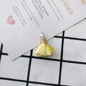 Detail of floral fabric petal pendant with pearl and gold cap on checkered background