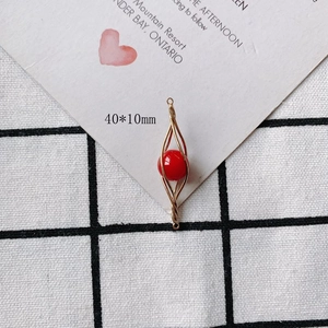 Detail of a 40x10mm gold spiral pendant with a red bead for DIY jewelry making
