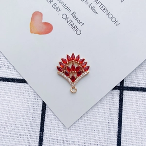 Macro shot of fan-shaped gold pendant with red marquise gems and white zircons