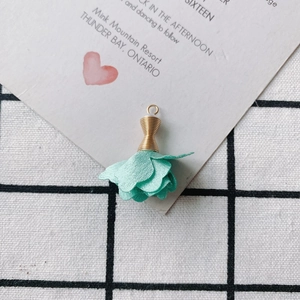 Vista macro de colgante de rosa de tela verde menta con hilo dorado para joyería DIY