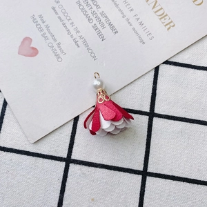 Close-up of red and white fabric flower pendant with a pearl and golden metal cap