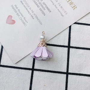 Macro shot of light purple fabric flower pendant with a white pearl and gold metal cap