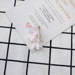 Détail d'un pendentif fleur en tissu rose clair avec fermoir en métal doré