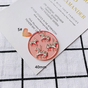 Detail view of 40mm pink acrylic portrait relief pendant with carousel enamel charms