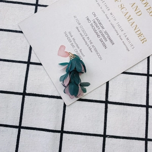 Détail de pendentif fleur en tissu avec pétales vert foncé et calotte métallique dorée