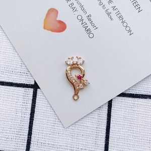 Macro detail of gold-plated alloy charm with pink gem and white marquise-cut zircons
