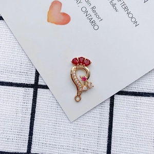 Macro detail of gold DIY jewelry pendant with red pear-cut stones and white crystals