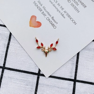 Detalle del colgante de reno dorado con piedras rojas marquise y cristales verdes