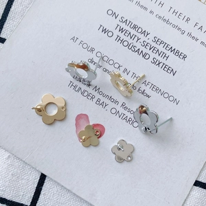 Flat lay of gold and silver hollow flower charms and earring studs on a rustic card