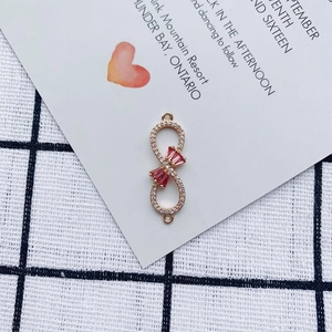 Macro detail of infinity gold pendant with red bow gemstone and crystal pavé accents